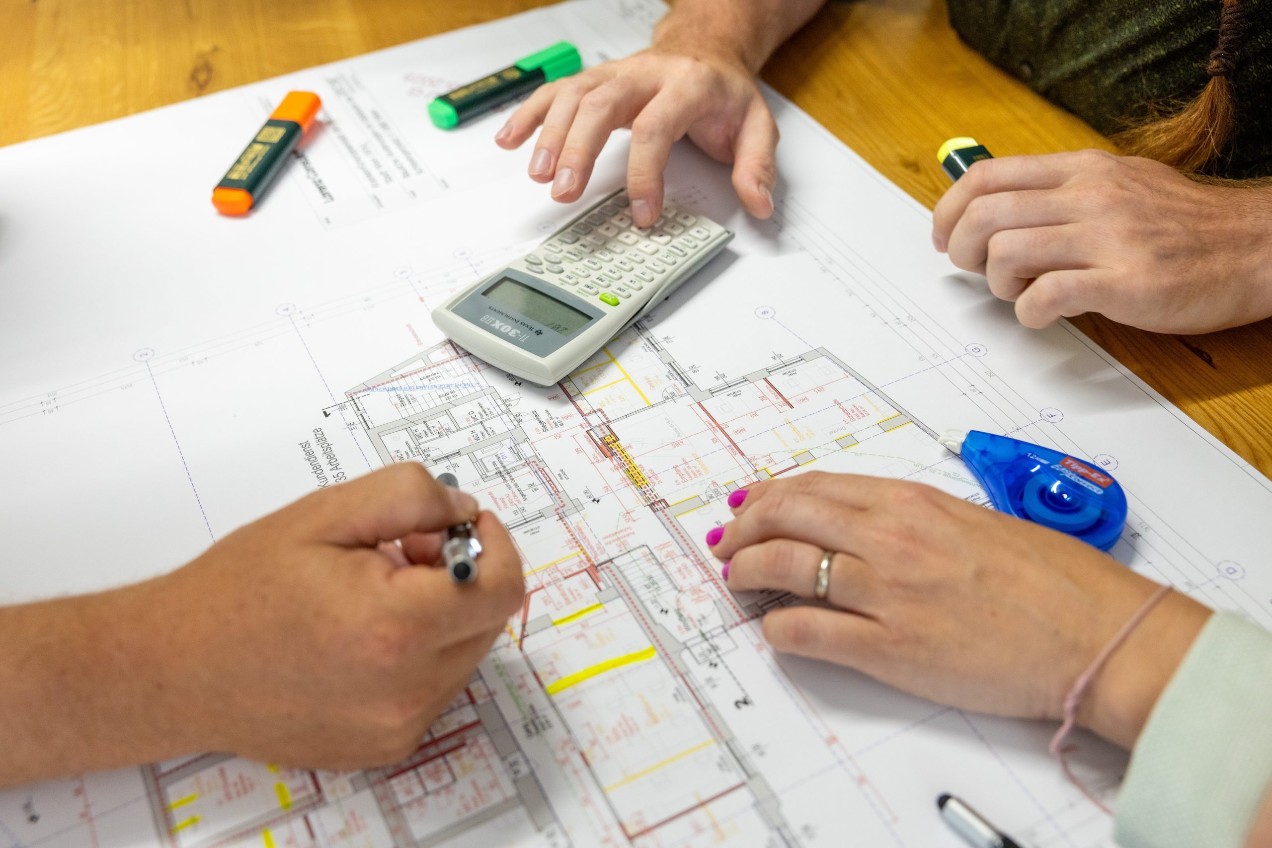 drei Menschen arbeiten an einem Bauplan